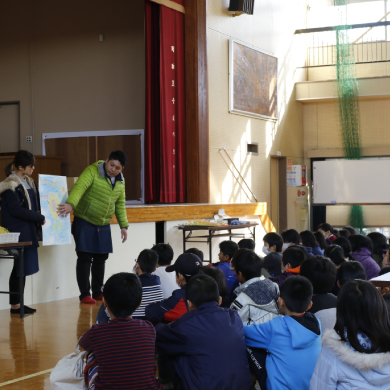 小学校の体育館で小学生にひまわりの花について説明している様子